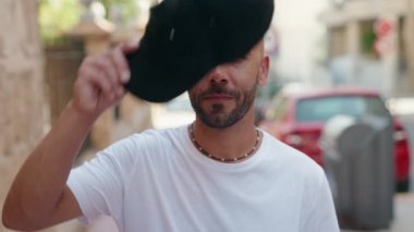 Genç kel adam gülümsüyor. Sokakta kendine güveni tam.