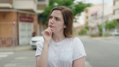 Young woman standing with doubt expression at street