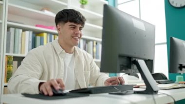 Young hispanic man student using computer studying at library university