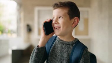 Sarışın çocuk okulda akıllı telefondan konuşuyor.