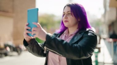 Genç ve cüsseli kadın gülümsüyor. Caddedeki dokunmatik yerde özçekim yapıyor.