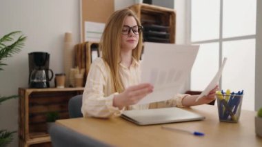 Genç sarışın iş kadını ofiste belge okuyor.