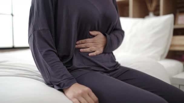 若いです中国人女性苦しみのために胃の痛み座っています上のベッドルーム — ストック動画