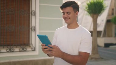 Sokakta dokunmatik ped kullanan, kendine güvenen İspanyol genç adam.