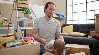Baba ve oğul yeni evlerinde karton kutuları açıyorlar.