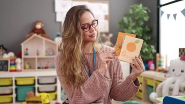 Young beautiful hispanic woman preschool teacher having vocabulary lesson at kindergarten