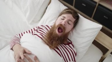 Genç kızıl saçlı adam yatakta uzanıyor, yatak odasında uyuyor.