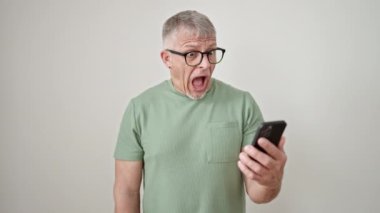 Orta yaşlı, kır saçlı, akıllı telefon kullanan, izole edilmiş beyaz arka plan üzerinden dolar tutan bir adam.
