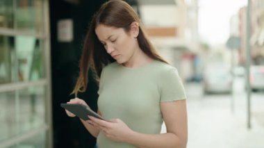 Young beautiful woman smiling confident using touchpad at street