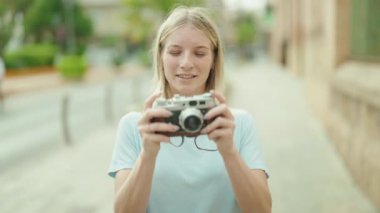 Sokakta klasik kamera kullanan genç sarışın kadın turist.