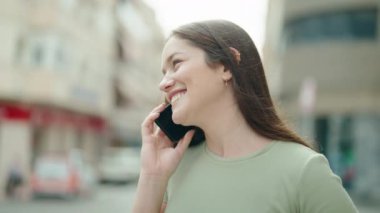 Genç, güzel bir kadın, gülümsüyor. Kendine güveniyor. Akıllı telefondan konuşuyor.