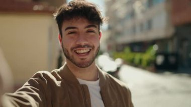 Young hispanic man smiling confident having video call at street