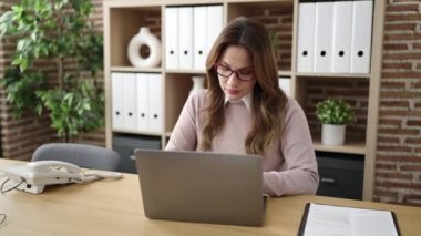 Genç, güzel İspanyol iş kadını ofiste dizüstü bilgisayar kullandığını vurguladı.