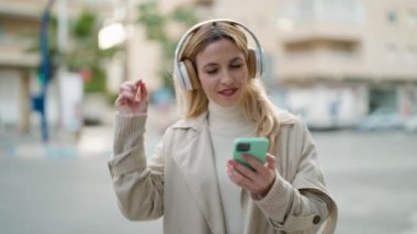 Sokakta müzik dinleyen kendine güvenen genç sarışın kadın.