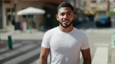 Sokakta kollarını kavuşturmuş genç Latin bir adam.