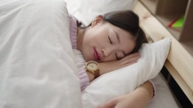 Young chinese woman lying on bed sleeping at bedroom