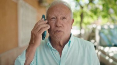 Kıdemli gri saçlı adam akıllı telefondan konuşuyor. Sokakta nöbet tutuyor.