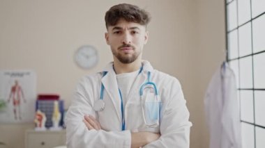 Genç Arap doktor gülümsüyor. Kollarını kavuşturup klinikte duruyor.