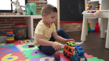 Adorable toddler playing with car toy sitting on floor at kindergarten