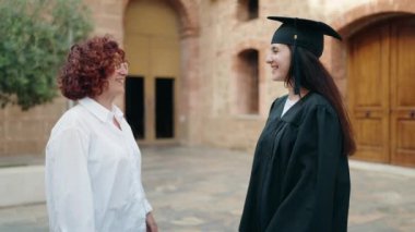 İki kadın anne ve kız, kampüs üniversitesinde birbirlerine sarılıyorlar.