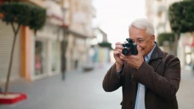 Orta yaşlı çift sokakta profesyonel kamera kullanarak fotoğraf çekiyor.