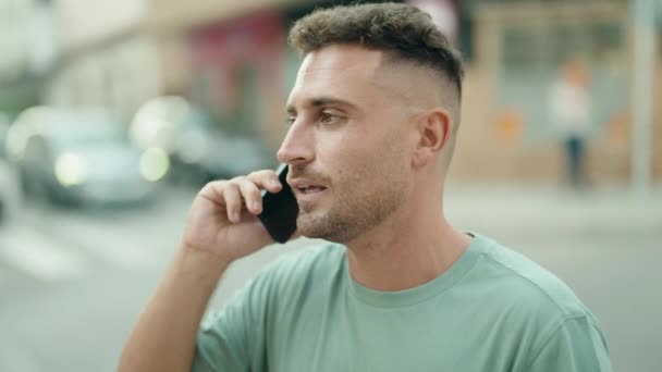 若いヒスパニック系の男が路上でスマートフォンで自信を持って話して笑っている — ストック動画