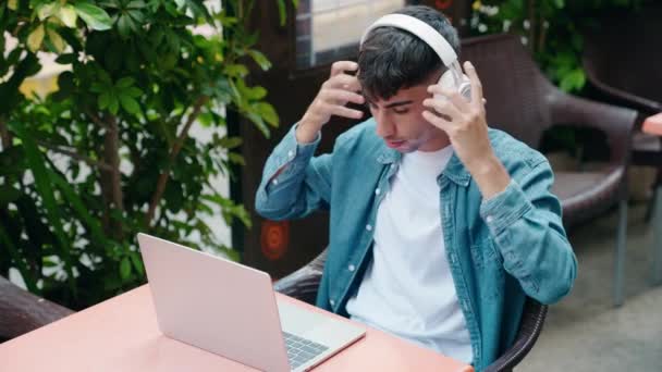 Joven Hispano Usando Laptop Auriculares Sentados Mesa Terraza Cafetería — Vídeos de Stock