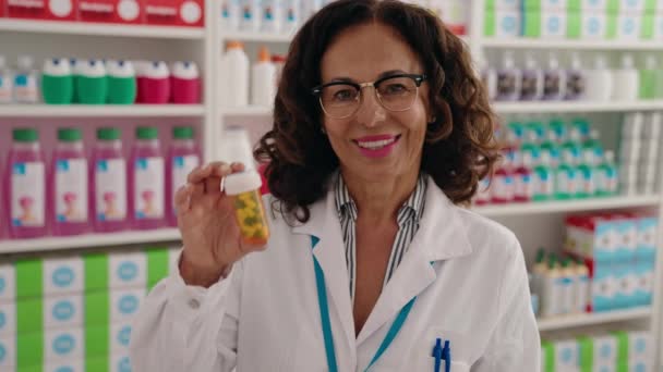 Middelbare Leeftijd Vrouw Apotheker Glimlachen Zelfverzekerde Holding Pillen Fles Bij — Stockvideo