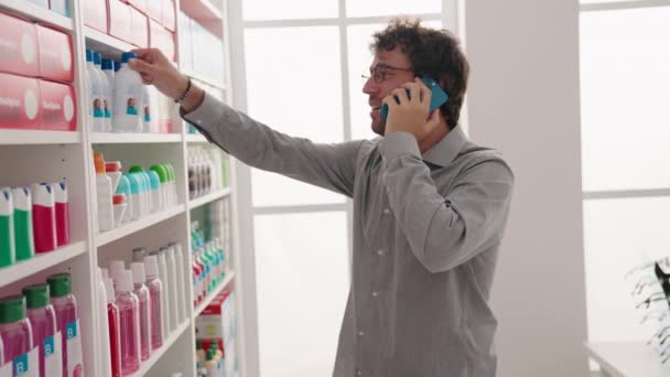 Jovem Hispânico Homem Cliente Falando Smartphone Segurando Garrafa Farmácia — Vídeo de Stock
