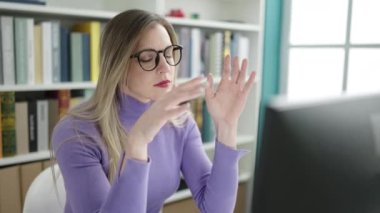 Kütüphane üniversitesinde bilgisayar kullanan sarışın genç bir kız.