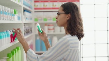 Genç Afrikalı Amerikalı kadın müşteri eczanede diş macunu şişesini seçiyor.