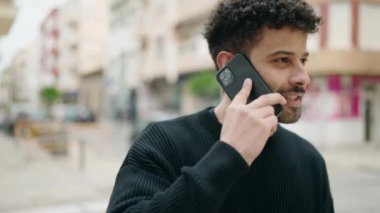 Genç Arap adam gülümsüyor, kendinden emin bir şekilde caddedeki akıllı telefondan konuşuyor.