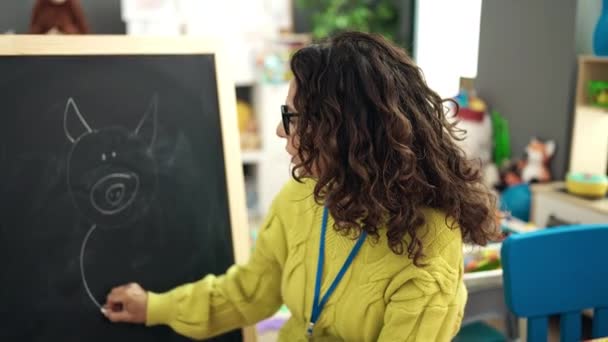 在幼儿园的黑板上画画的中年惊慌失措的幼儿园女教师 — 图库视频影像