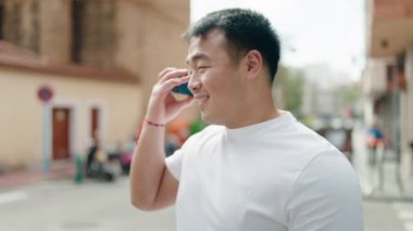 Genç Çinli adam gülümsüyor. Caddedeki akıllı telefondan kendine güvenen bir sesli mesaj dinliyor.