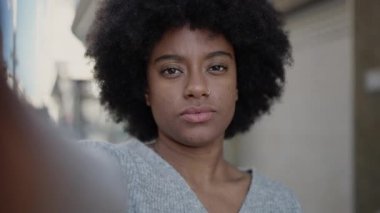 Afro-Amerikalı kadın gülümsüyor. Sokakta kamerayla özçekim yapıyor.