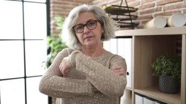 Middle age woman with grey hair business worker smiling confident standing with arms crossed gesture at office