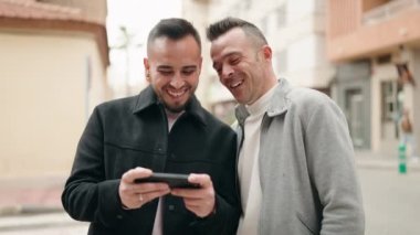 Sokakta akıllı telefondan video izleyen genç çift.