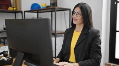 Genç, güzel, İspanyol bir iş adamı ofiste bilgisayar kullanarak iş yapıyor.