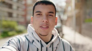 Genç adam gülümsüyor. Sokaktan video çağrısı alıyor.