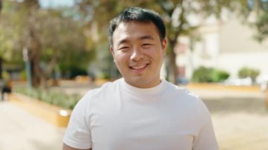 Young chinese man smiling confident breaking dollar at park