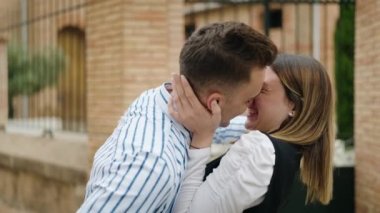 Man and woman couple hugging each other kissing at street