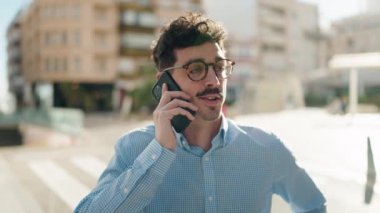 Genç İspanyol adam gülümsüyor. Kendine güveniyor. Sokakta akıllı telefondan konuşuyor.