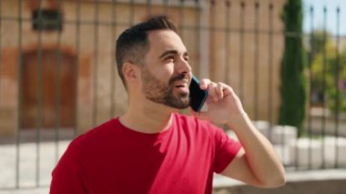 Genç İspanyol adam gülümsüyor. Kendine güveniyor. Sokakta akıllı telefondan konuşuyor.