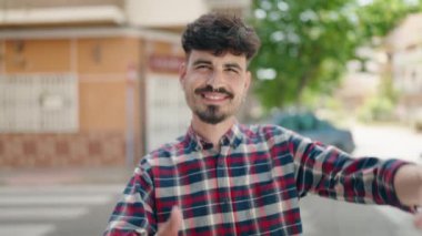 Young hispanic man smiling confident doing photo gesture with hands at street