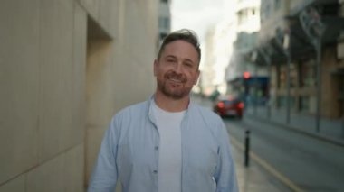 Sokakta kendine güvenen beyaz bir adam gülümsüyor.