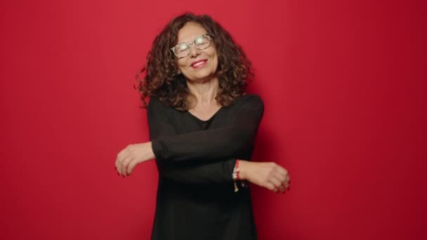 Orta Yaşlı Bir Kadın Gülümsüyor Kırmızı Arka Planda Kendine Sarılıyor — Stok video
