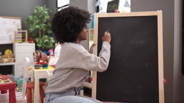 African American Woman Teacher Smiling Confident Writing Blackboard Kindergarten — 图库视频影像