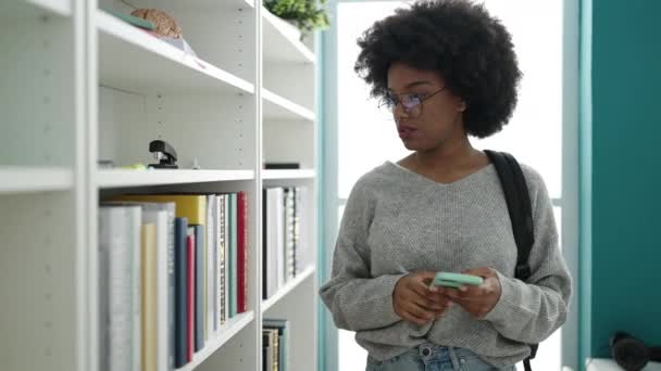 Africano Americano Mulher Estudante Procura Livro Usando Smartphone Universidade Biblioteca — Vídeo de Stock