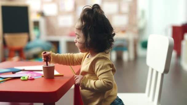 Adorable Hispanic Girl Student Sitting Table Putting Pencil Color Cup — Vídeo de Stock