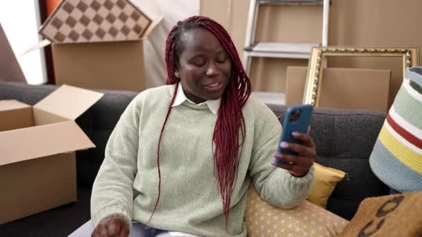 在新家的沙发上 一个留着辫子的非洲女人正在做视频通话 — 图库视频影像
